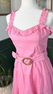A pink ruffled strap dress with a tiered skirt and a woven belt buckle.