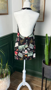 Black halter-neck romper with a vibrant collage print of vintage postcards and floral motifs.