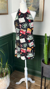Black halter-neck dress with a vibrant, eclectic print of vintage postcards and floral motifs.