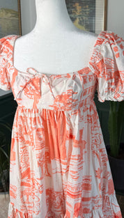 A coral and white printed dress with puffed sleeves and a square neckline.