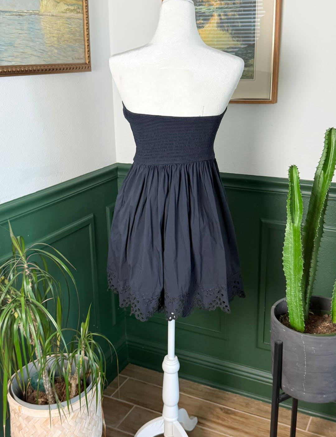 A navy blue strapless mini dress with a gathered waist and delicate eyelet lace trim at the hem.