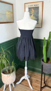 A navy blue strapless mini dress with a gathered waist and delicate eyelet lace trim at the hem.