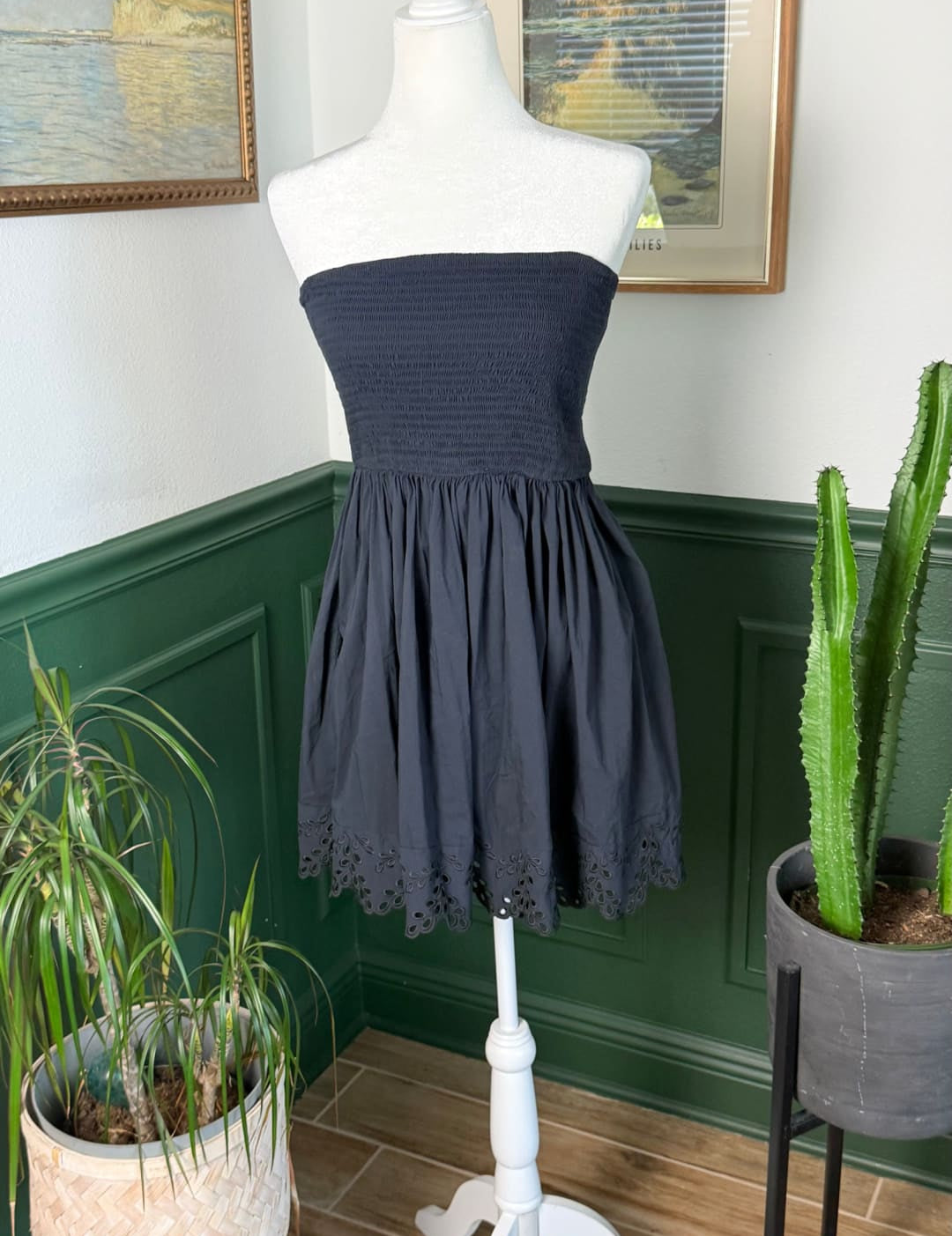 Navy blue strapless dress with a gathered bodice and eyelet lace trim at the hemline.