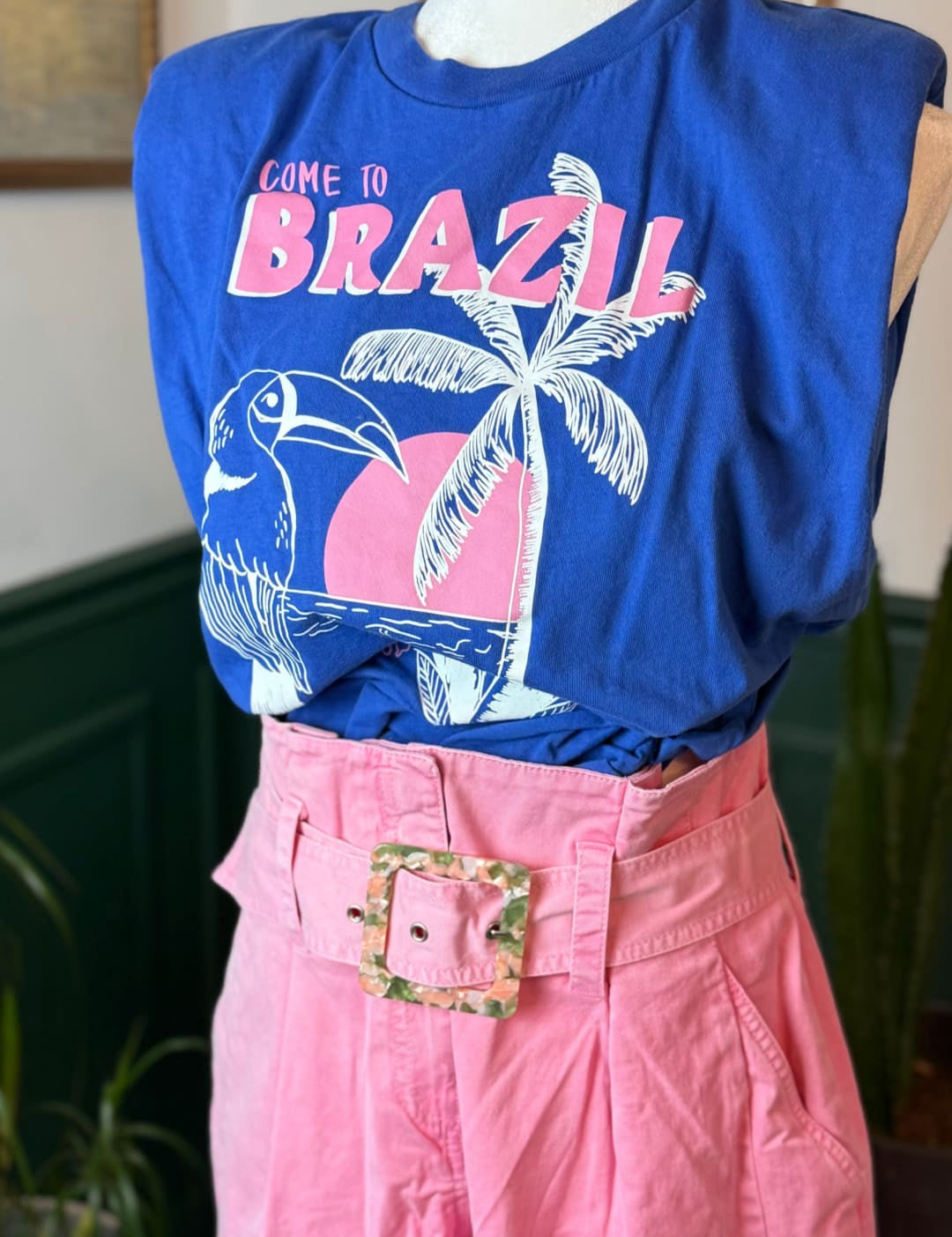 Blue sleeveless t-shirt with ’come to brazil’ graphic featuring a toucan and palm tree in pink, white, and blue.