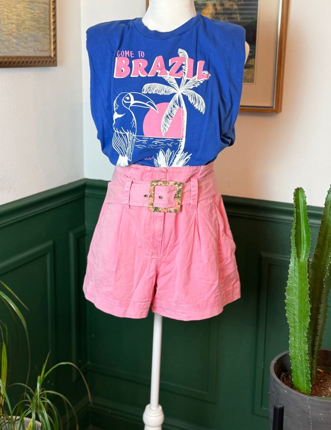 Pink pleated shorts with a gold-toned belt buckle.