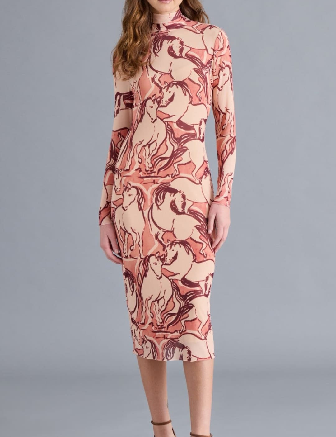 A long-sleeved, high-neck midi dress in a pink and brown horse print.