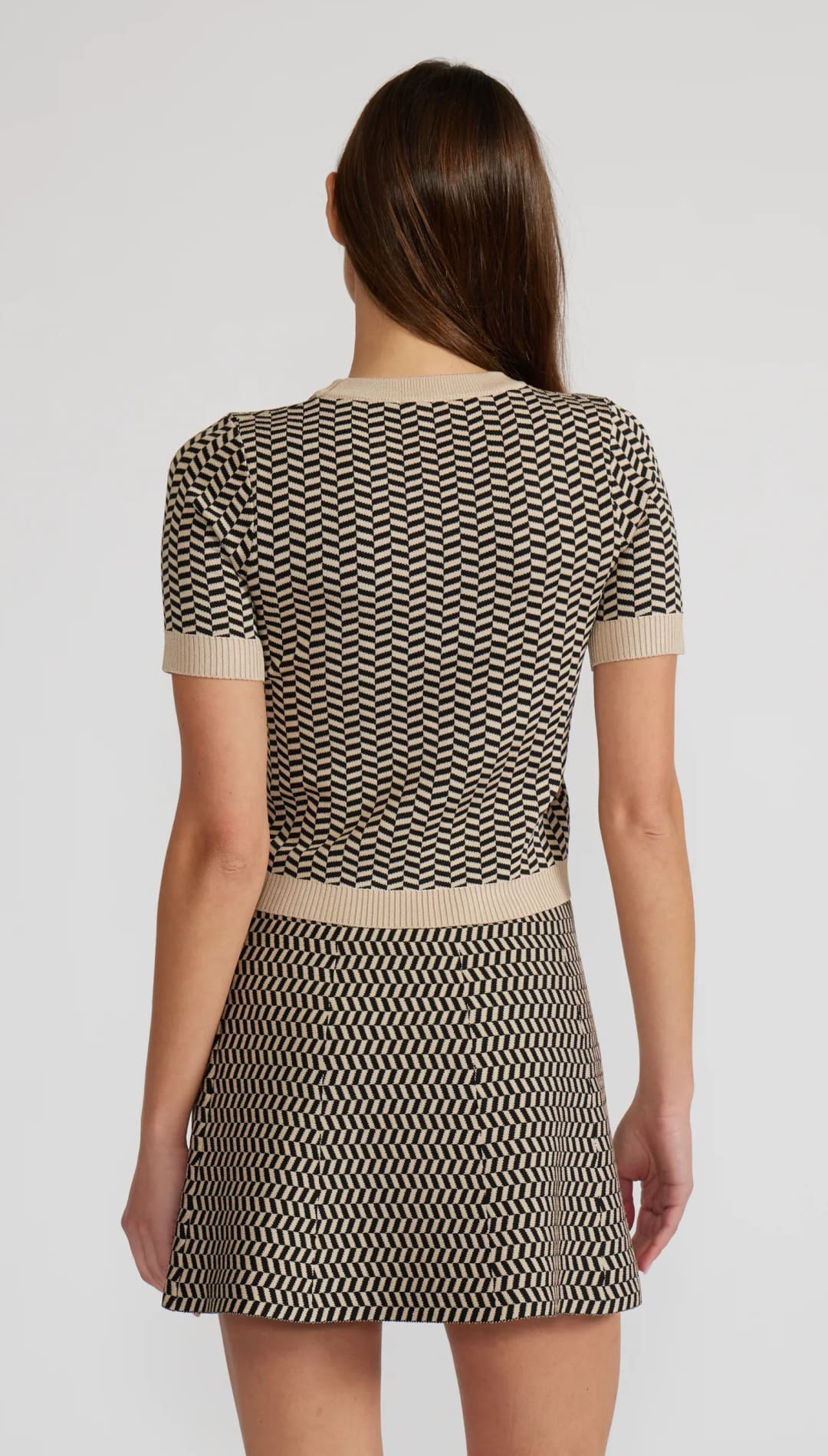 Woman in a two-piece beige and black chevron knit top and mini skirt.