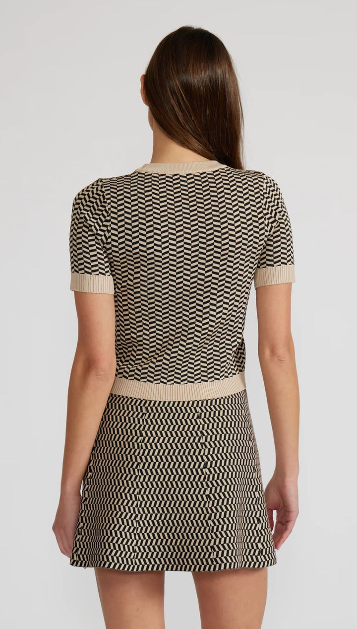 Woman in a two-piece beige and black chevron knit top and mini skirt.