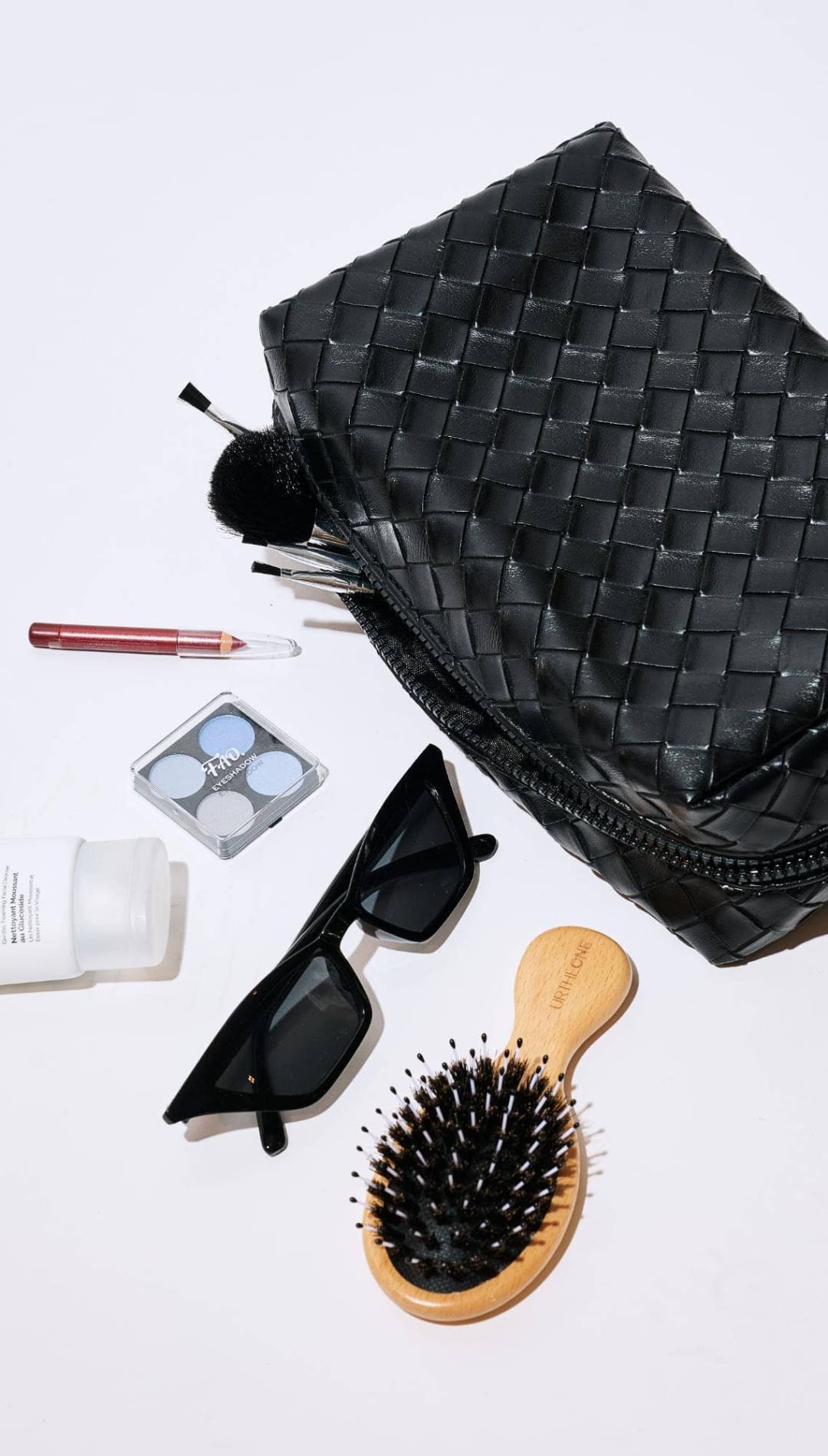 Black woven leather toiletry bag with zipper closure and handle.