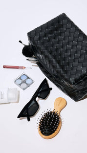 Black woven leather toiletry bag with zipper closure and handle.