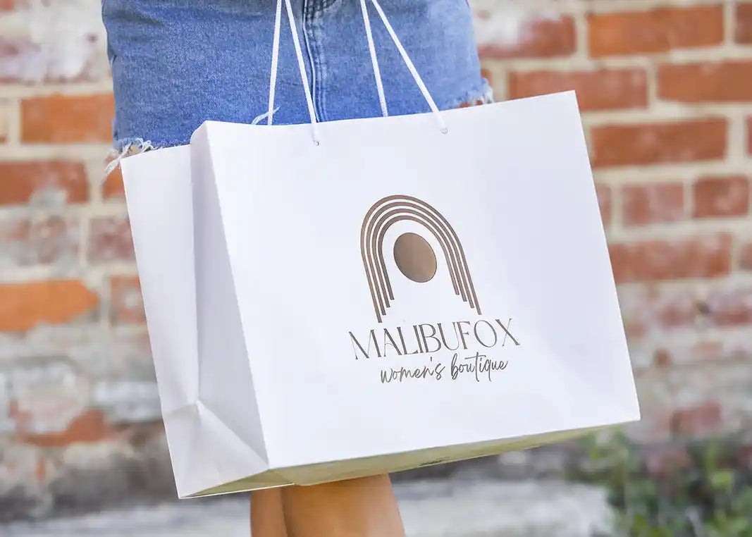 White shopping bag with a brown ’Malibufox’ logo design.