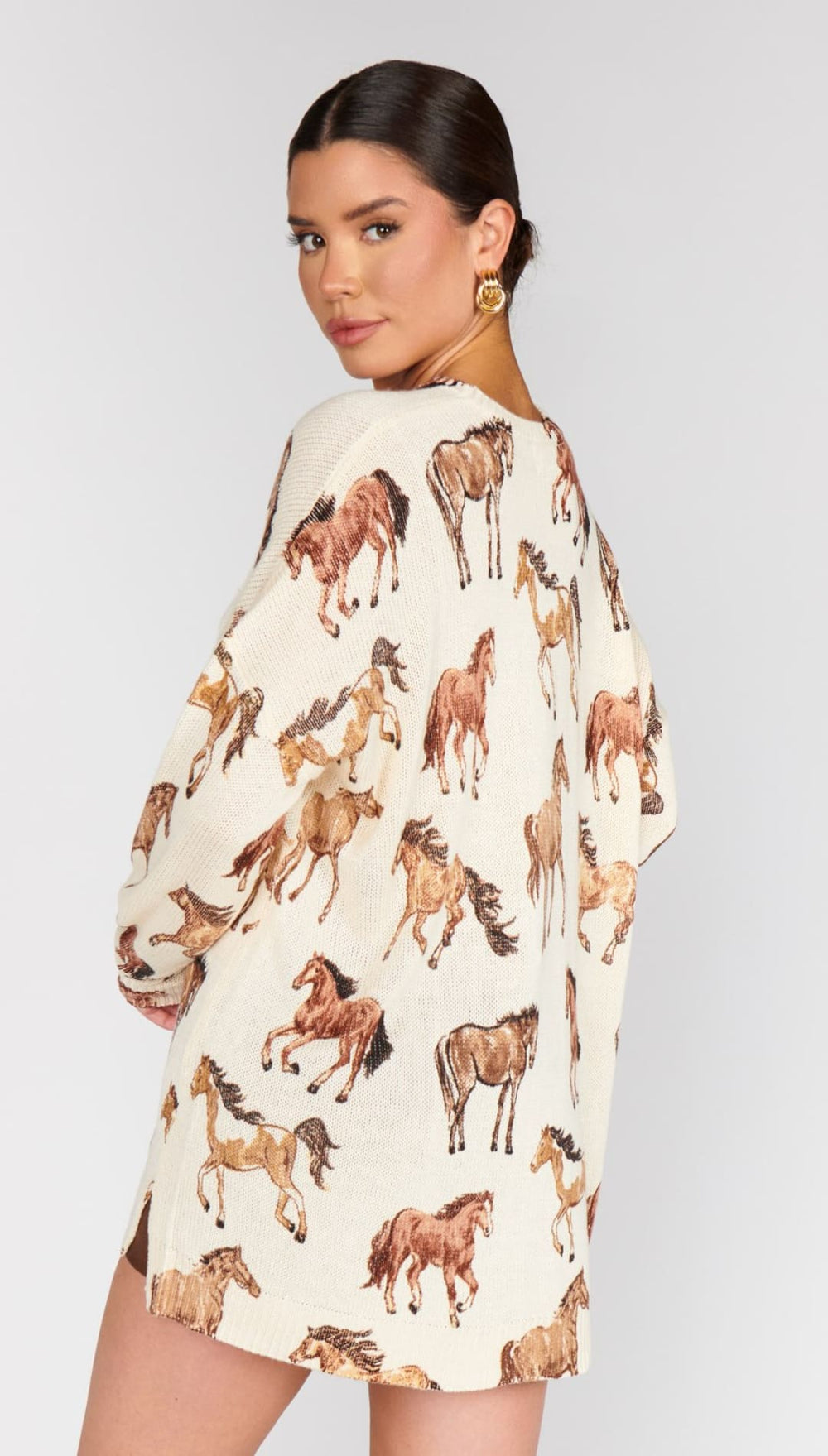 A woman’s cream-colored tunic or oversized shirt with a scattered brown horse print.