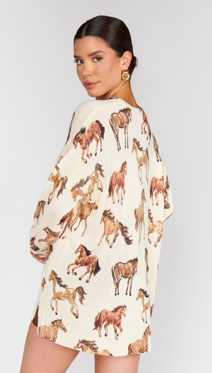 A woman’s cream-colored tunic or oversized shirt with a scattered brown horse print.
