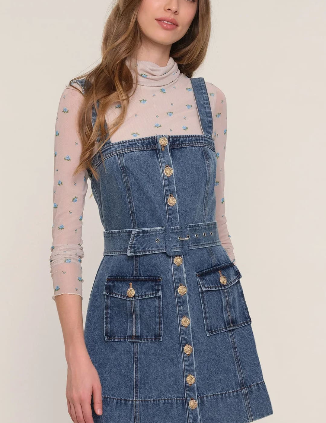A denim pinafore dress with a full button front, a belted waist, and large patch pockets.