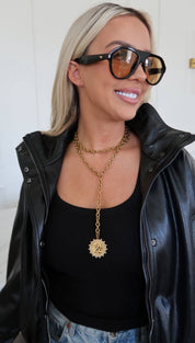 Gold chain necklace with a circular medallion pendant.