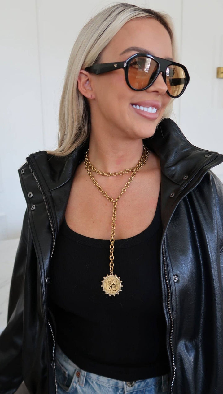 Gold chain necklace with a circular medallion pendant.
