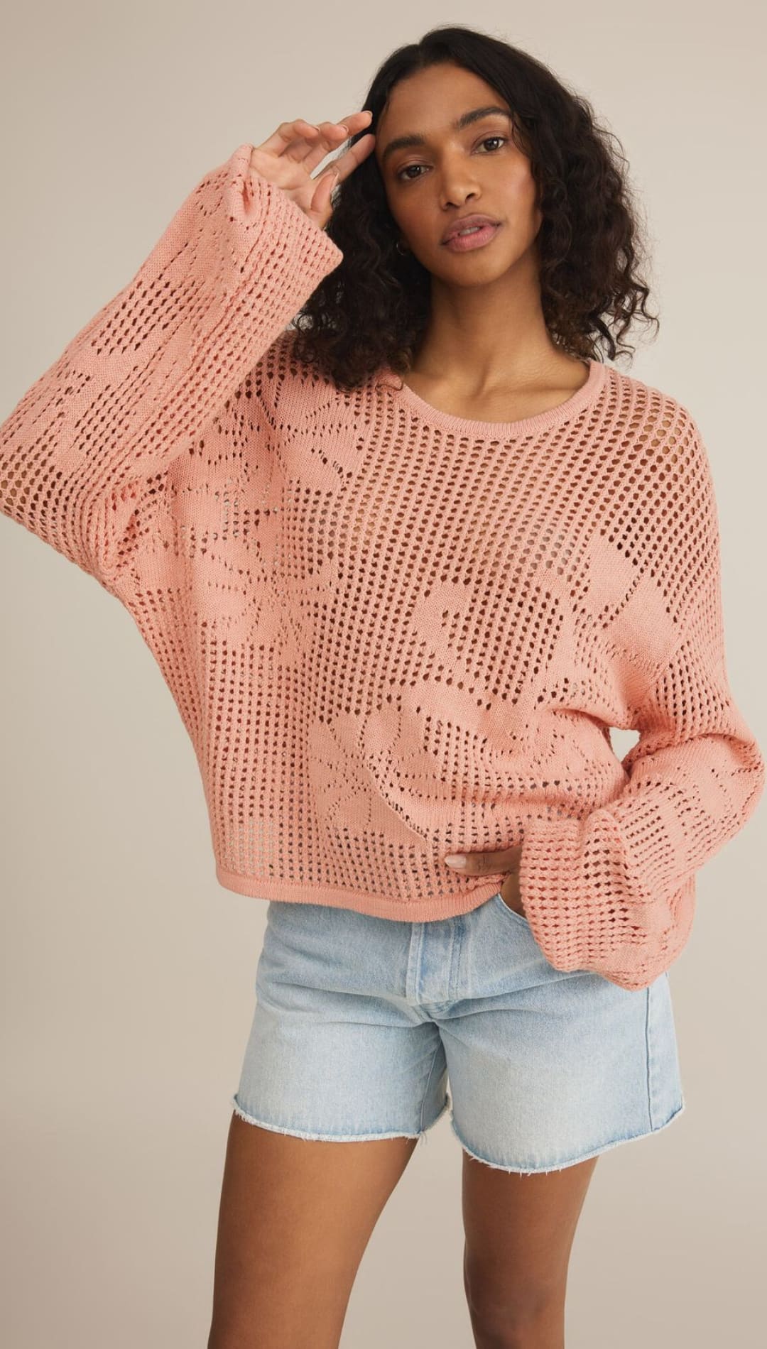 Peach-colored, open-knit sweater with floral design.