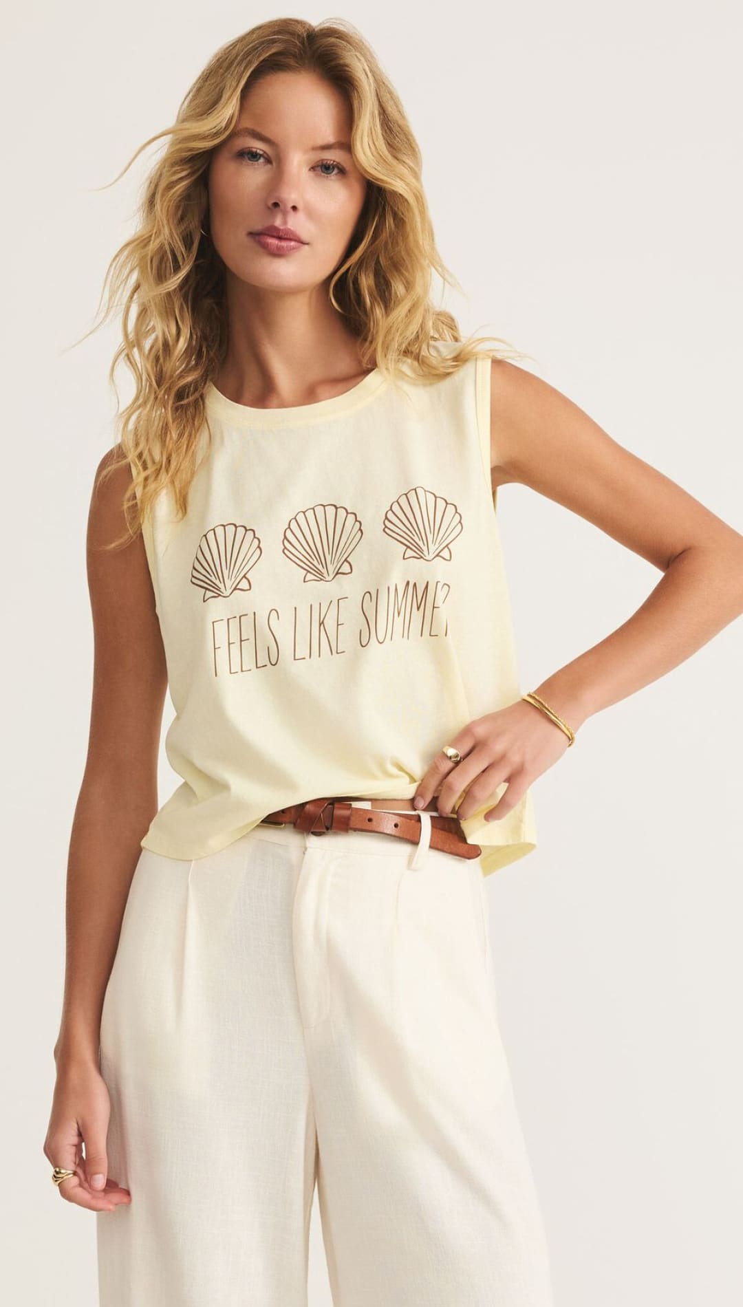 Woman in a yellow tank top with seashell graphic.