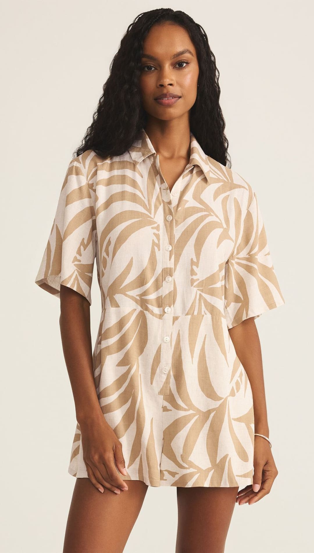 Leaf-patterned romper with short sleeves.