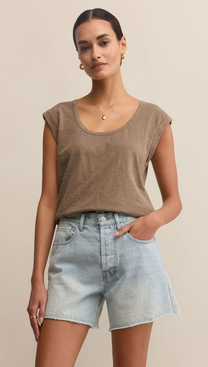 Woman wearing a brown top and denim shorts.