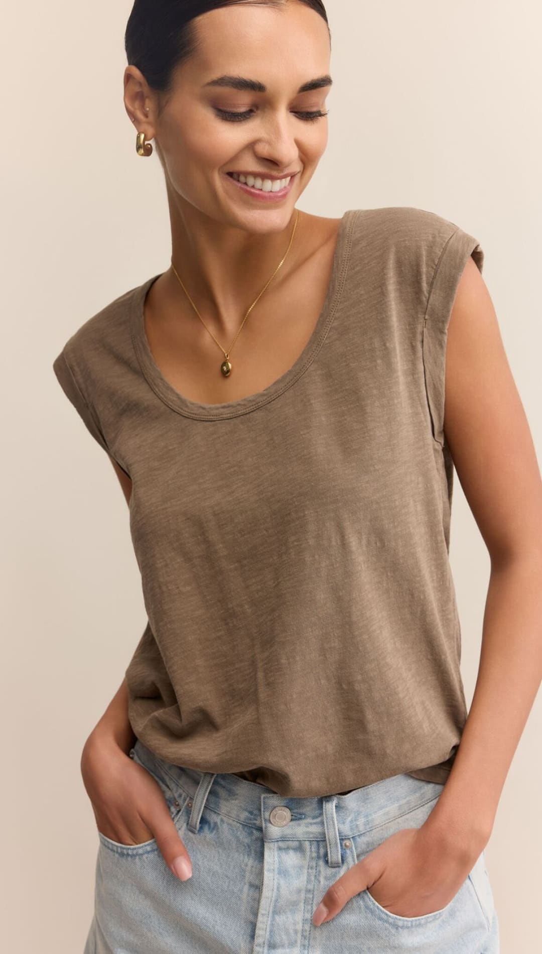 Woman in a brown sleeveless shirt and light blue denim shorts.