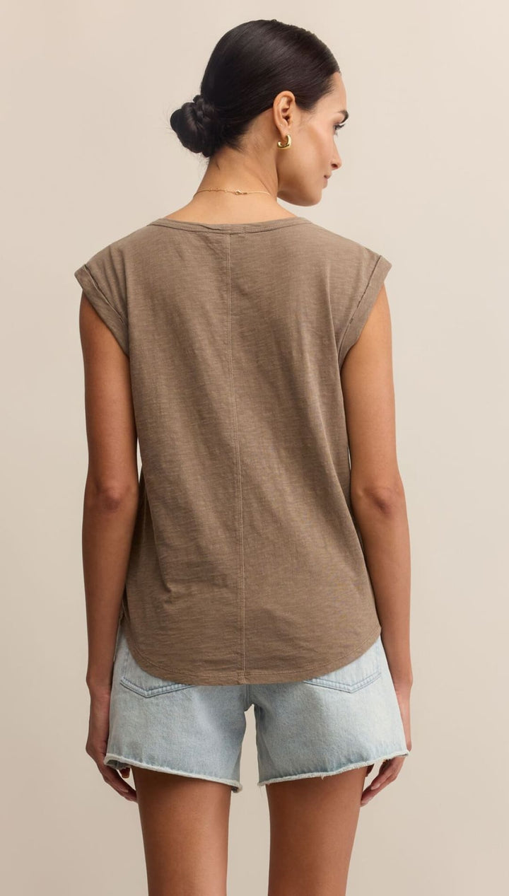 Woman wearing a brown t-shirt and light blue denim shorts.