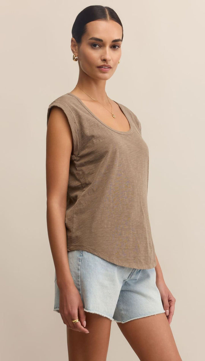 Woman wearing a brown tank top and denim shorts.