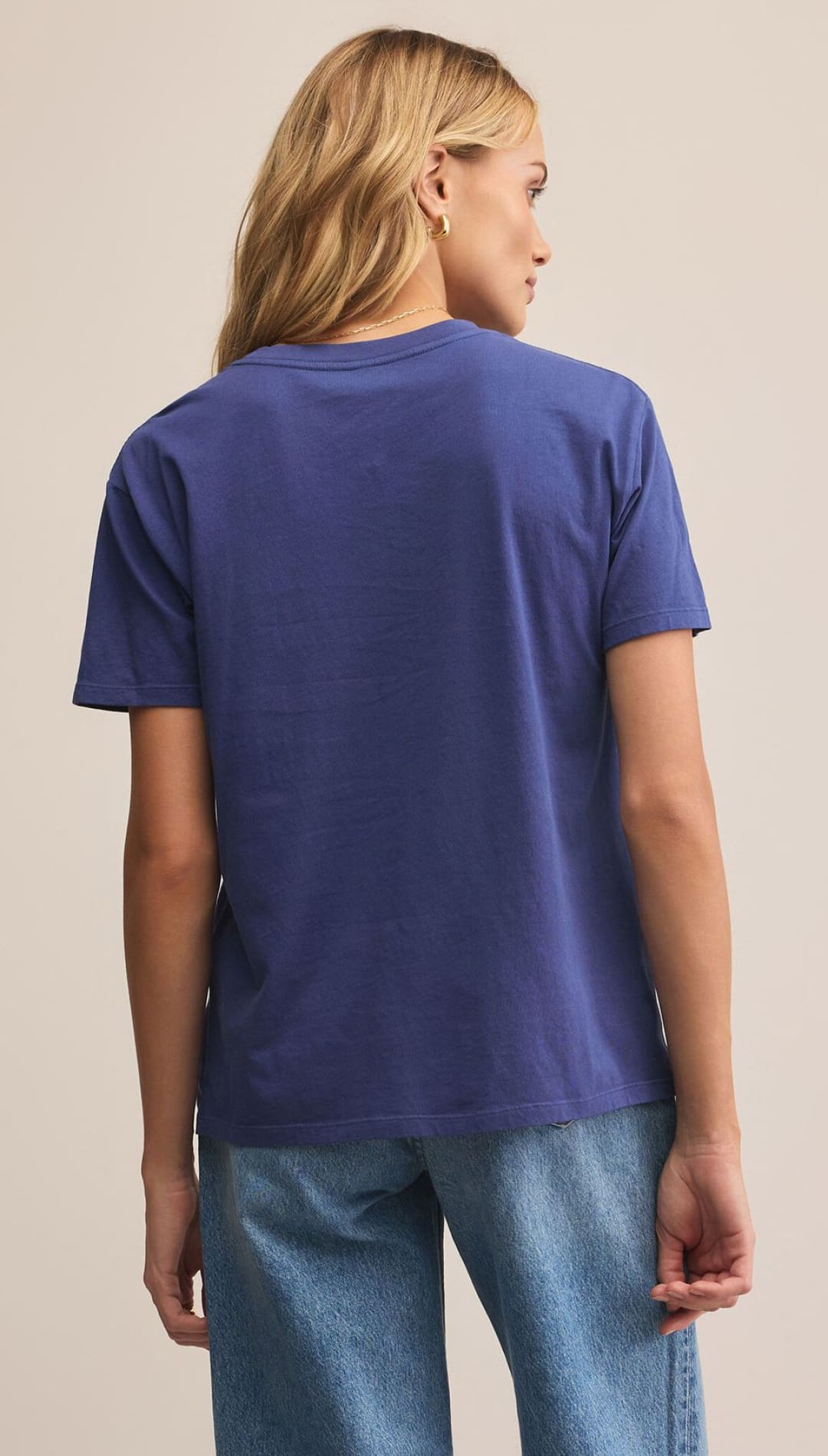 A woman’s short-sleeved blue t-shirt with a crew neck, paired with light wash blue jeans.