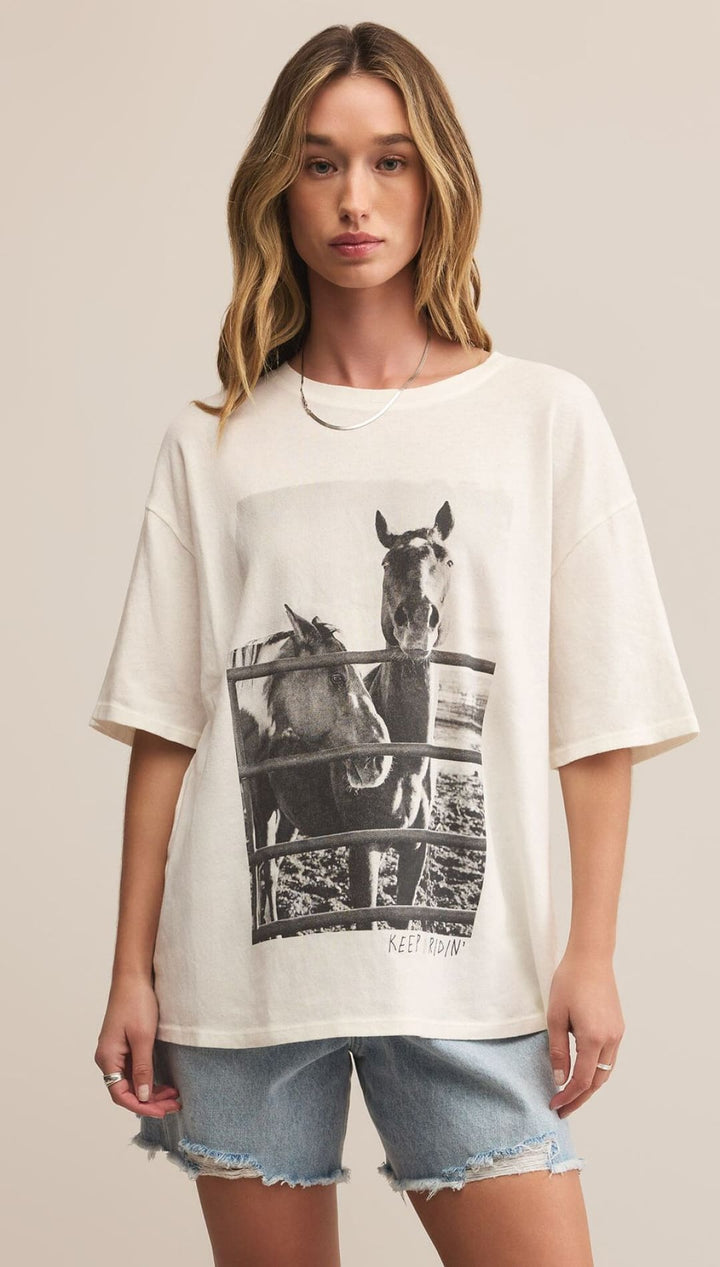 An off-white oversized t-shirt with a black and white photo print of two horses behind a fence.