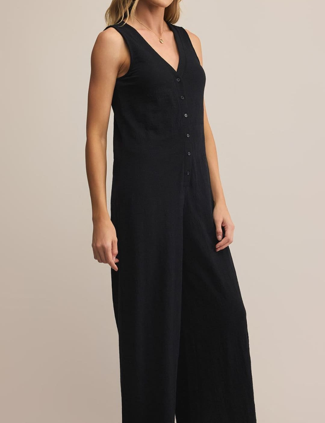 Black sleeveless jumpsuit with button-down front and wide-leg design.