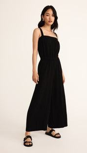 A black wide-leg jumpsuit with a smocked bodice and thick shoulder straps.