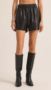 Black leather high-waisted shorts with a paperbag waistband and chunky heel boots.