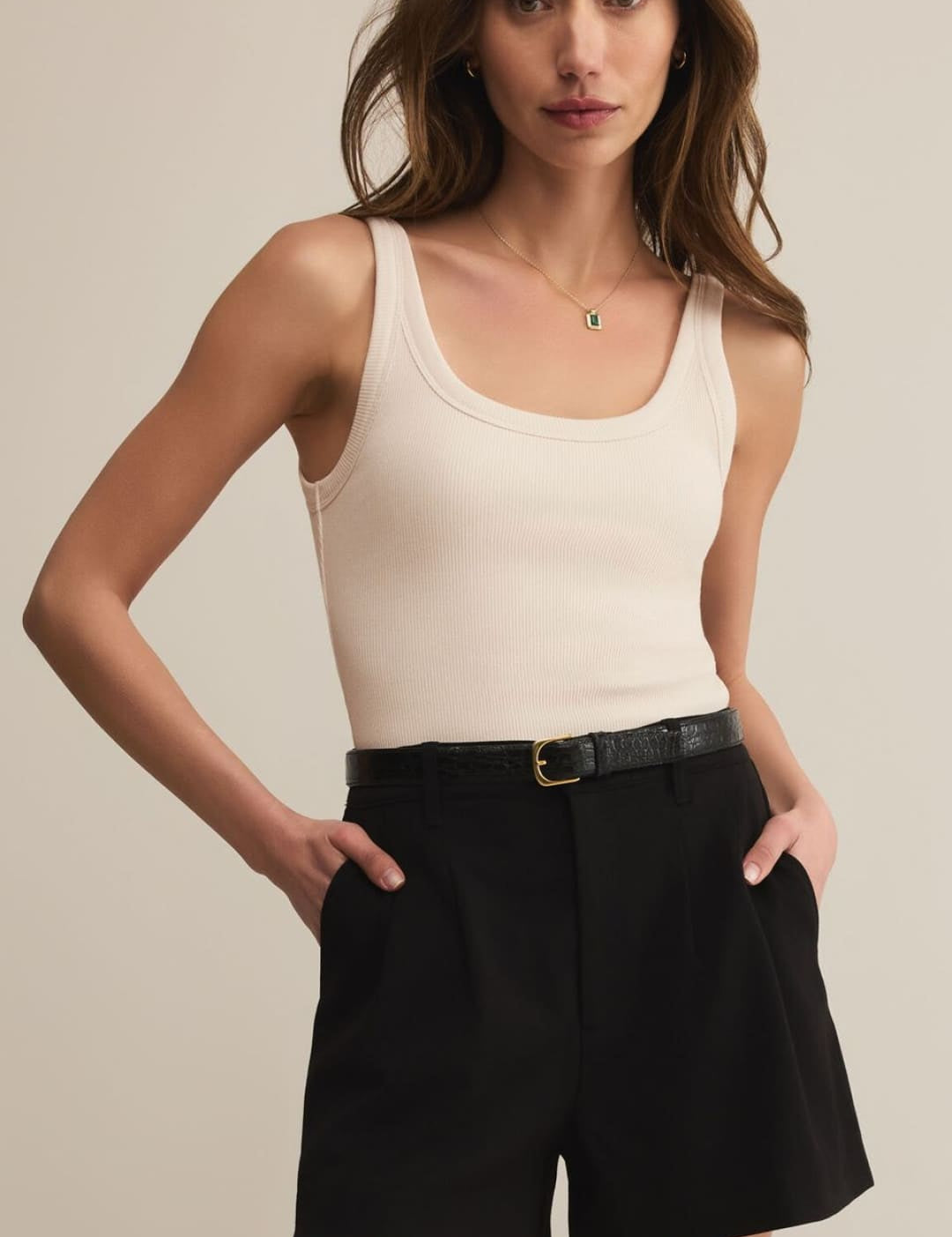 Cream ribbed tank top and black tailored shorts with a belt.