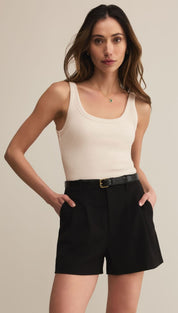 Cream ribbed tank top and black tailored shorts with a belt.