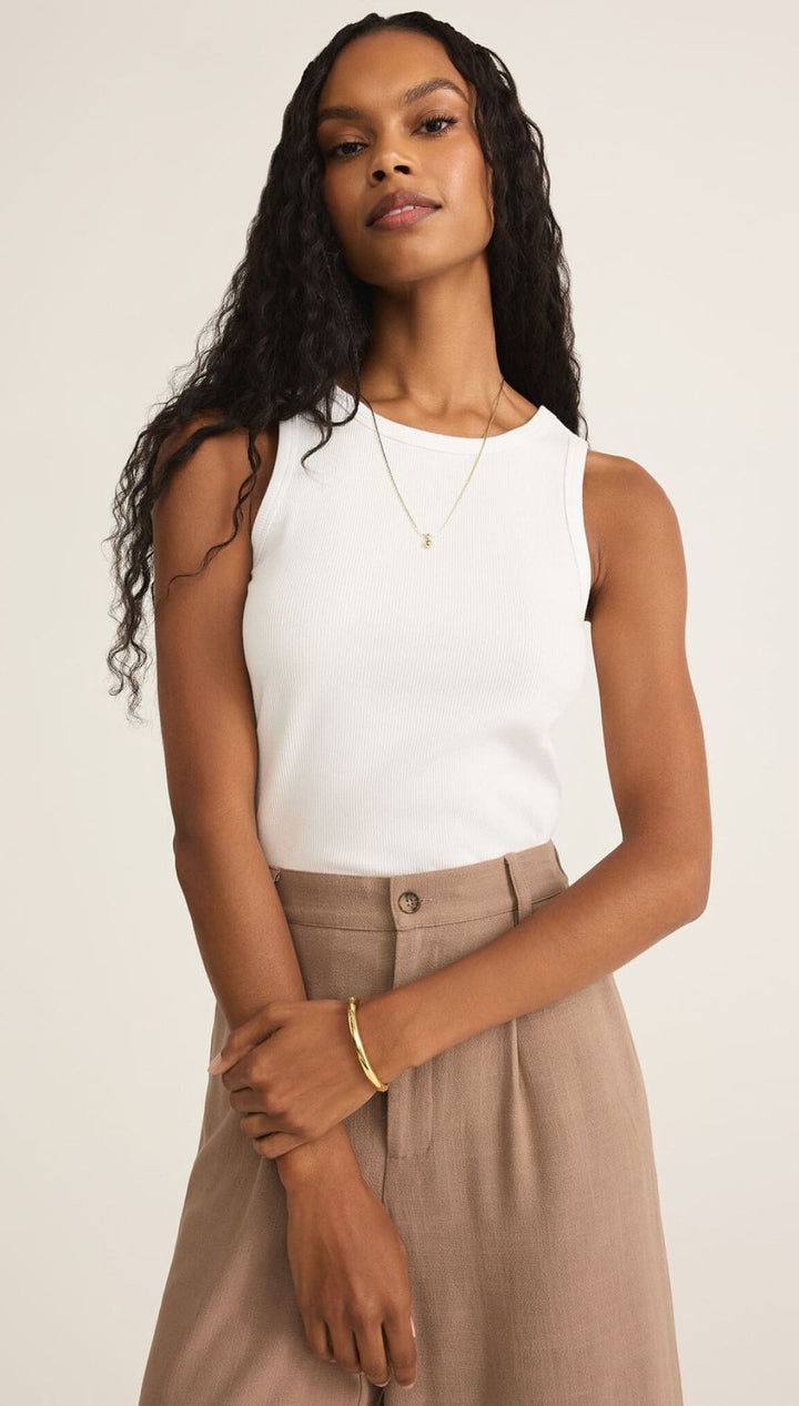 A woman modeling a white sleeveless top and light brown wide-leg pants.