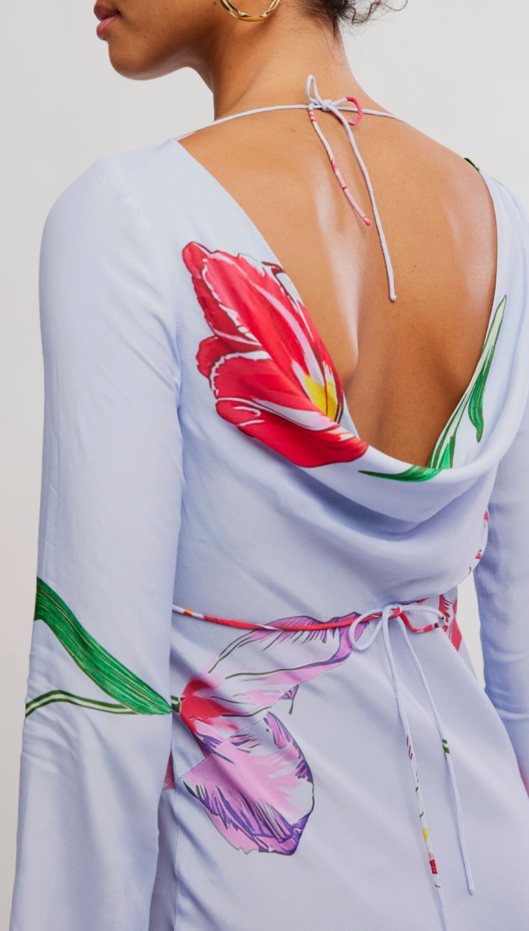 Light blue long-sleeved dress with vibrant red, pink, and green floral print featuring a deep back cutout tied at the neck.