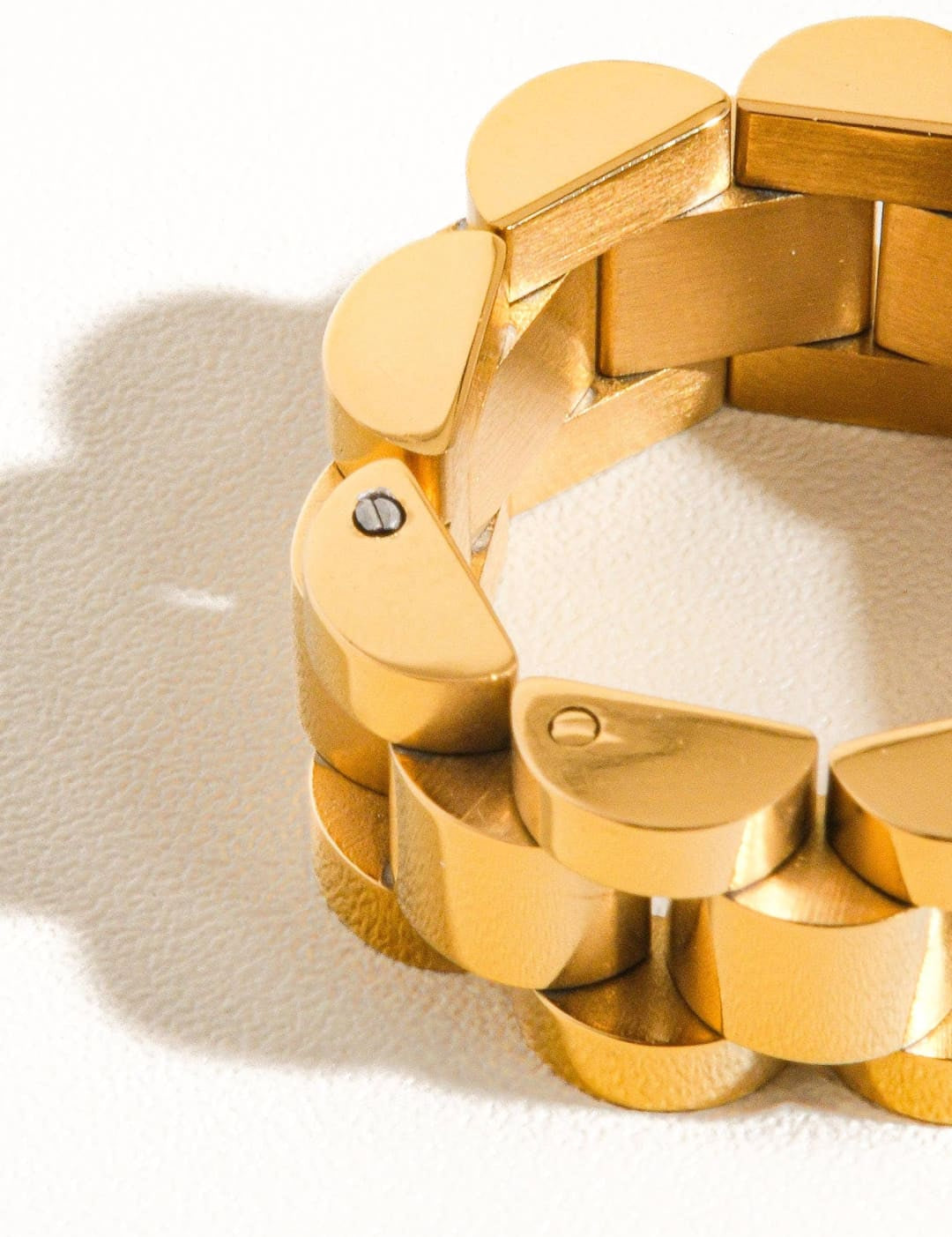 Gold-toned, interlocking semi-circular links form a sleek and modern expandable bracelet with a polished metallic finish.