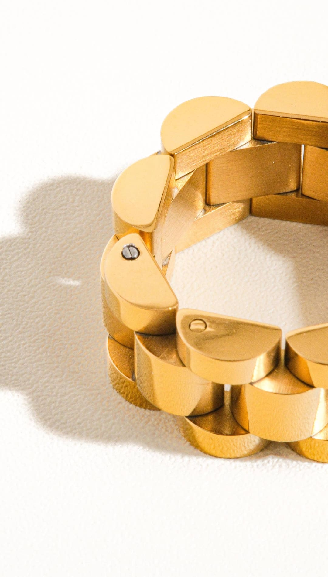 Gold-toned, interlocking semi-circular links form a sleek and modern expandable bracelet with a polished metallic finish.